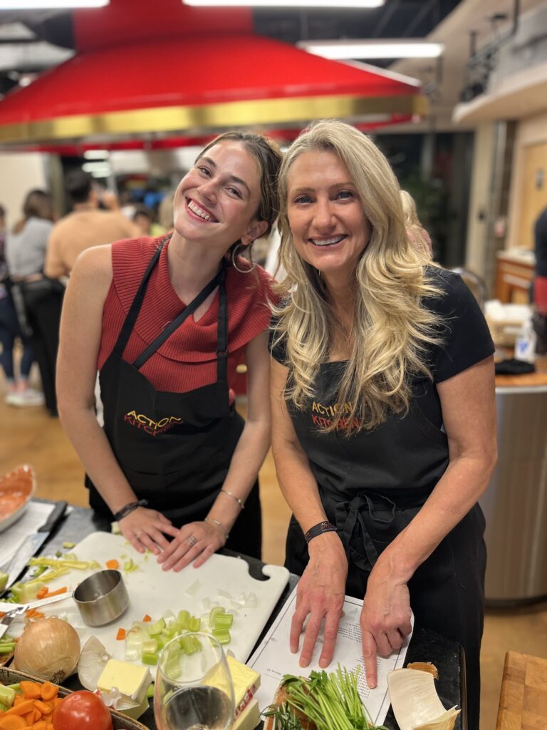 Two women posing in front of a shared cutting board